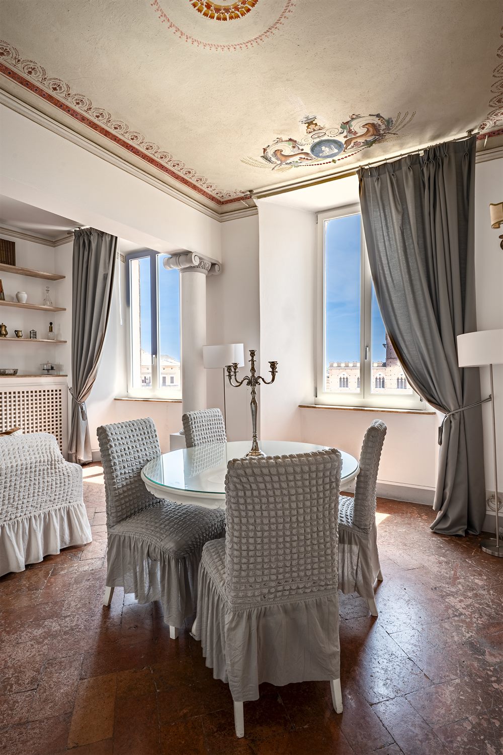Salotto con soffitto affrescato e colonna, due finestre sul Palazzo Pubblico